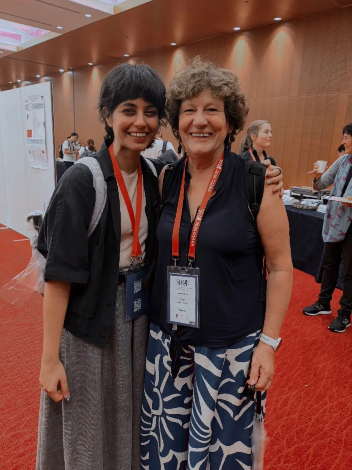 Two women with conference lanyards posing together