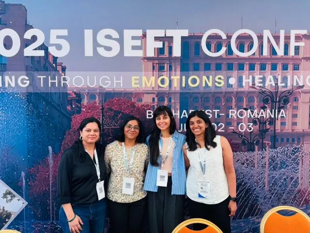 Four EFTii attendees in front of the 2025 isEFT Conference backdrop in Bucharest