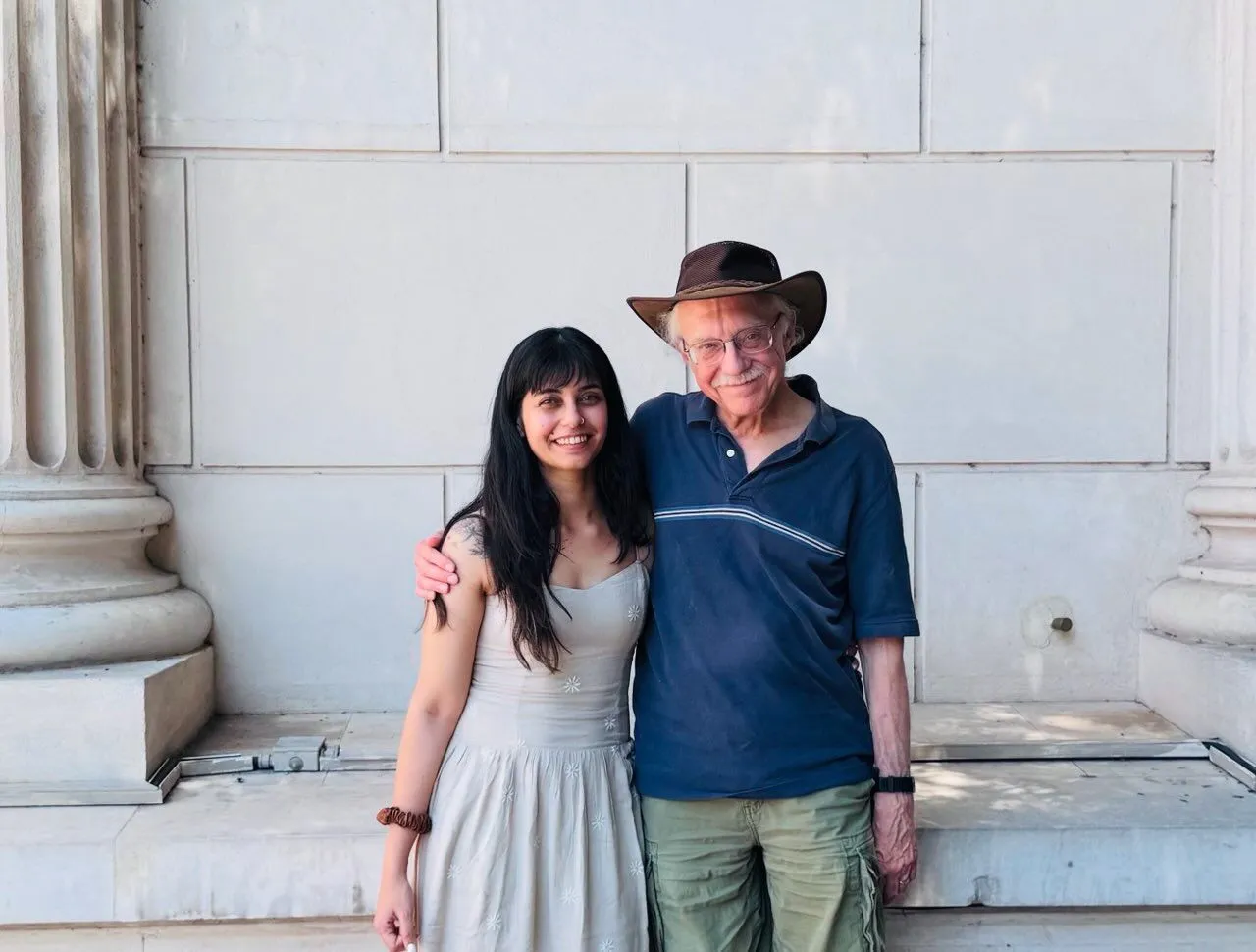A woman and an older man in a hat standing together outside