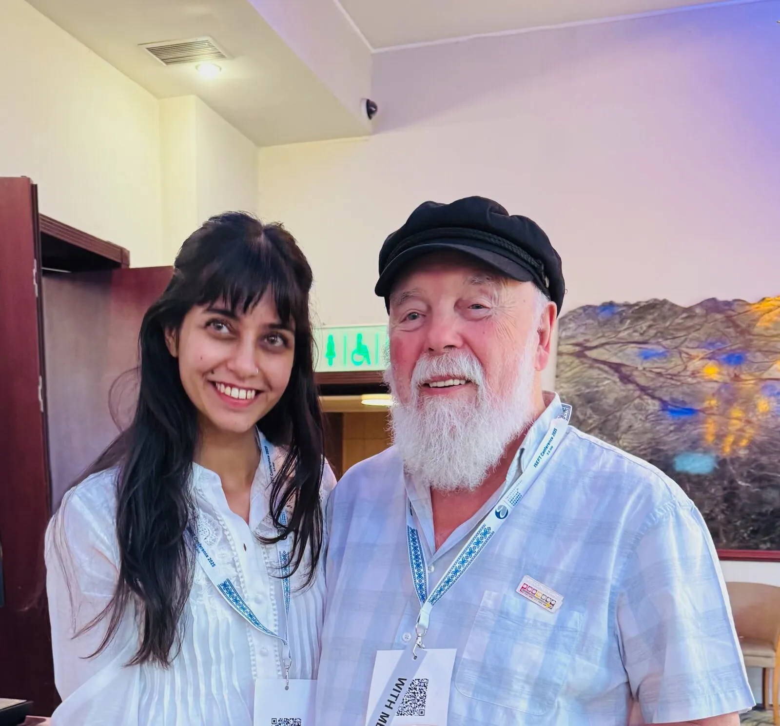 A woman and an older man with a white beard and cap smiling together